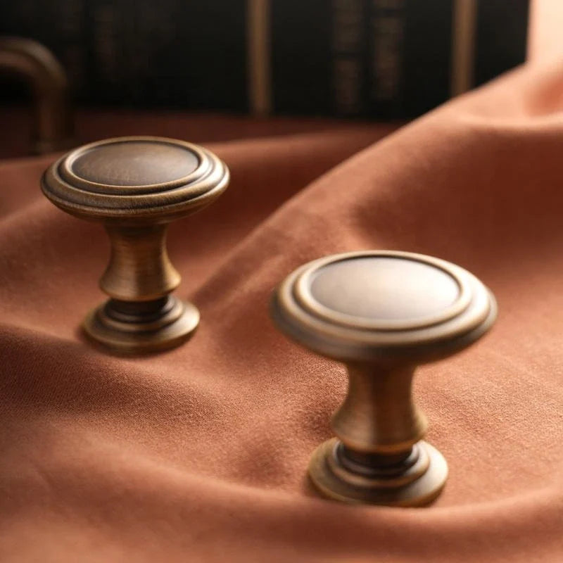 Two antique brass collared cabinet knobs on rust velvet
