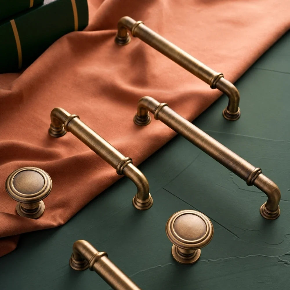 Antique brass collared cabinet pulls and knobs arranged on rust fabric