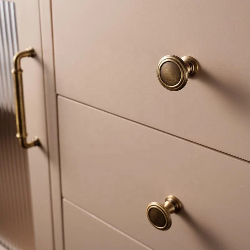 Close-up of antique brass collared knobs on cream cabinet doors