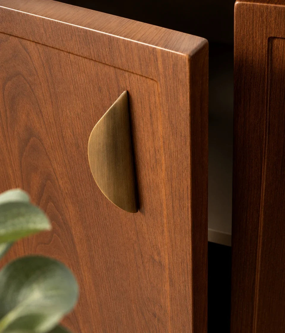 Antique brushed brass crescent pulls installed horizontally on beige drawers