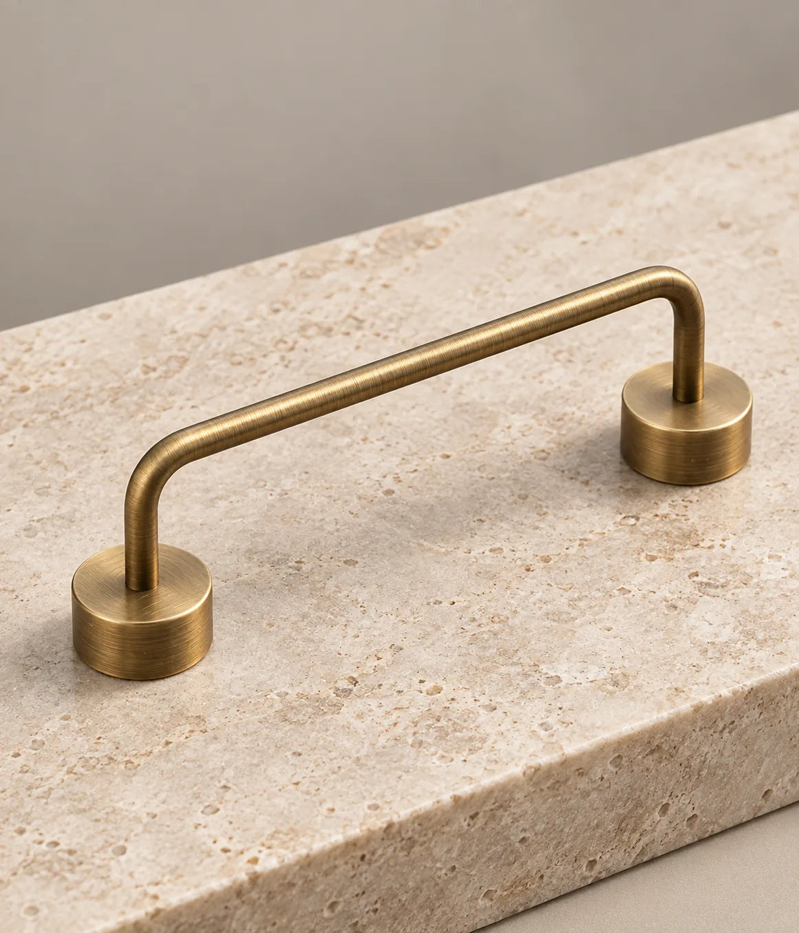 Detail of an antique brass bridge pull with a slim rounded bar and cylindrical mounting bases