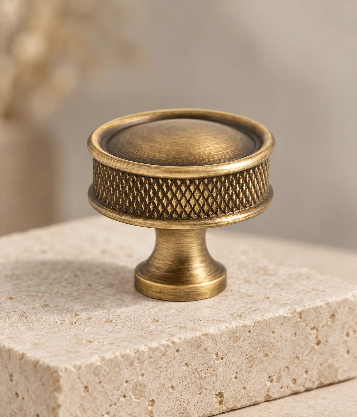 Close view of antique brass domed cabinet knob with textured grip and round mounting base