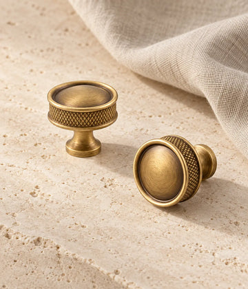 Antique brass domed cabinet knobs with diamond-knurled side bands on ivory stone