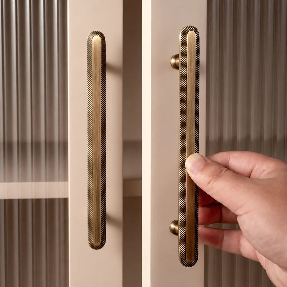 Antique brass knurled rim pulls installed on cream glass cabinet doors