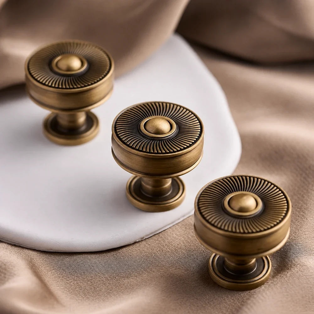 Antique brass sunburst knobs on a white display block