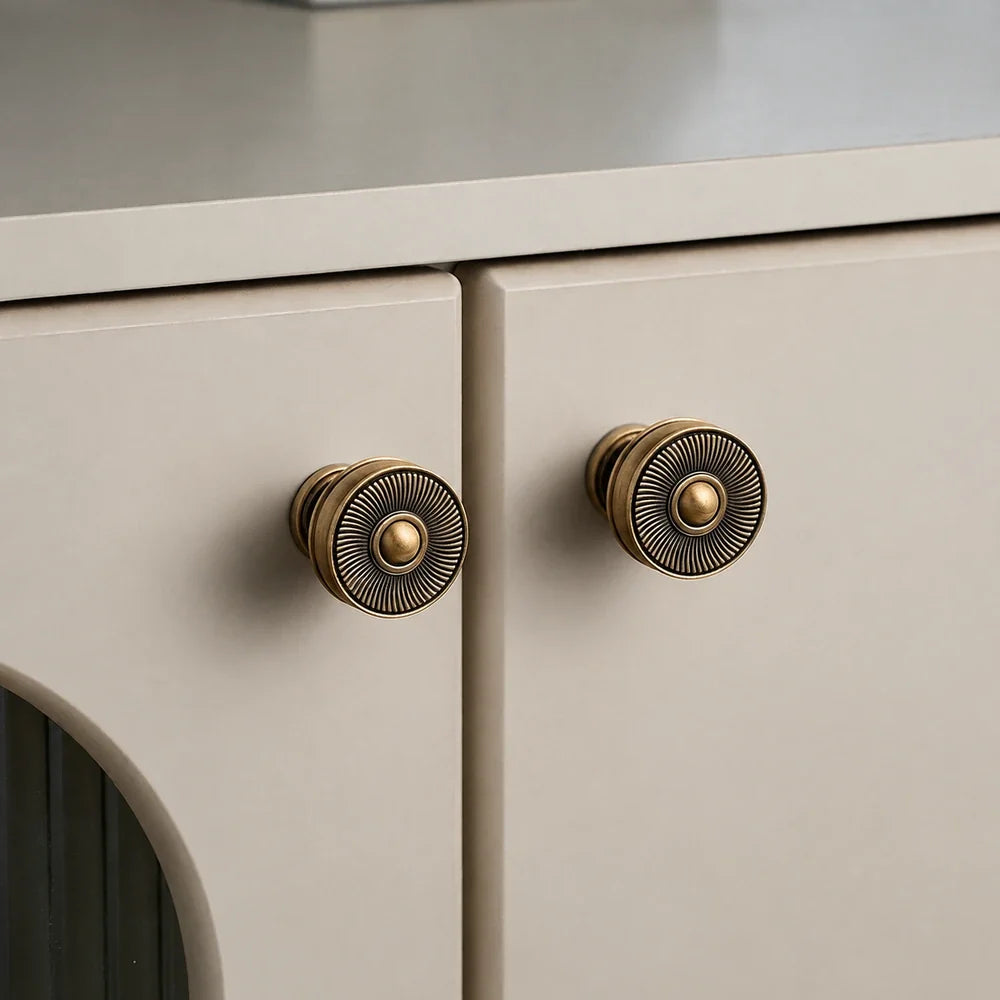 Antique brass sunburst knobs installed on cream cabinet doors