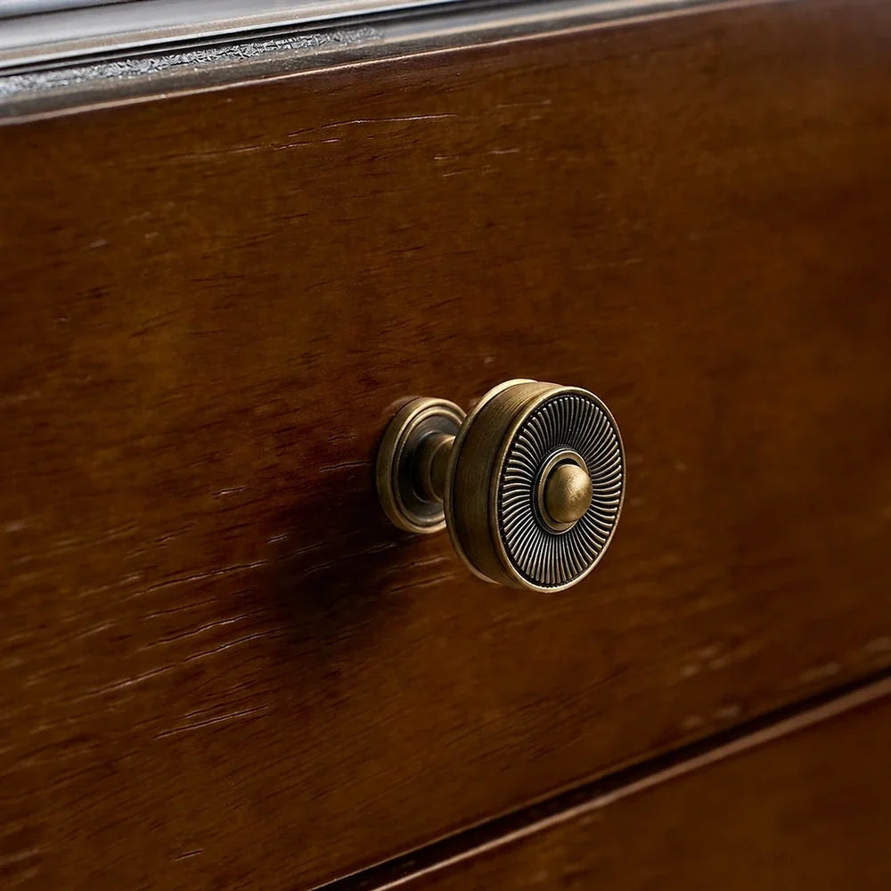 Close-up of an antique brass sunburst knob on a wood drawer
