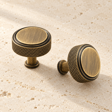 Solid Brass Knurled Cabinet Knob displayed on pale limestone.