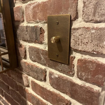 Brass light switch on a brick wall