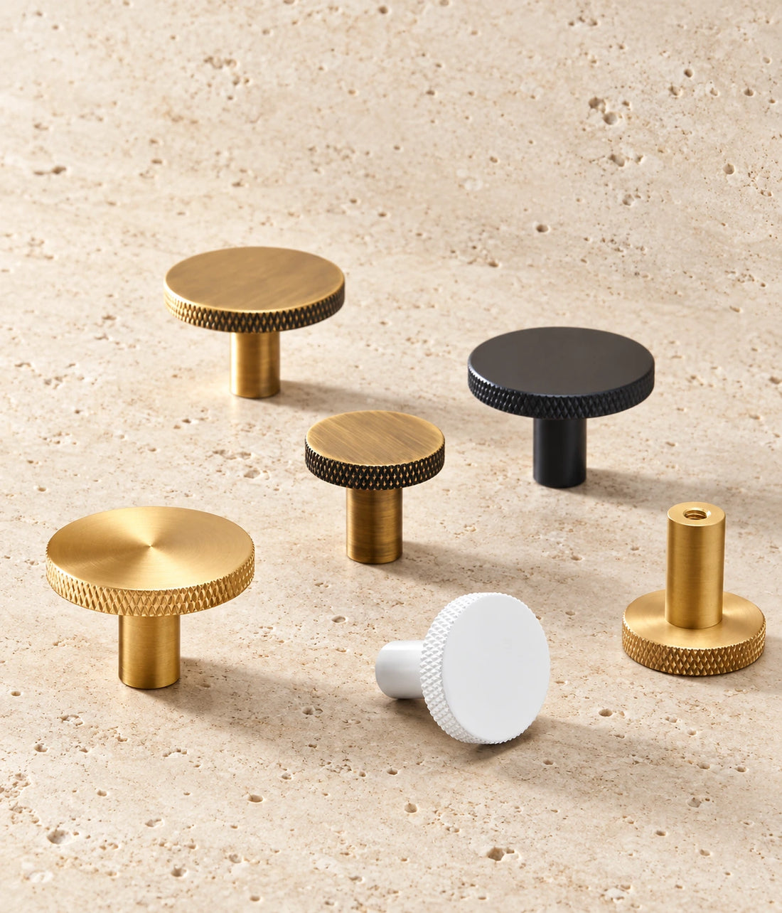 Knurled-Rim Brass Cabinet Knobs & Hooks arranged on warm limestone