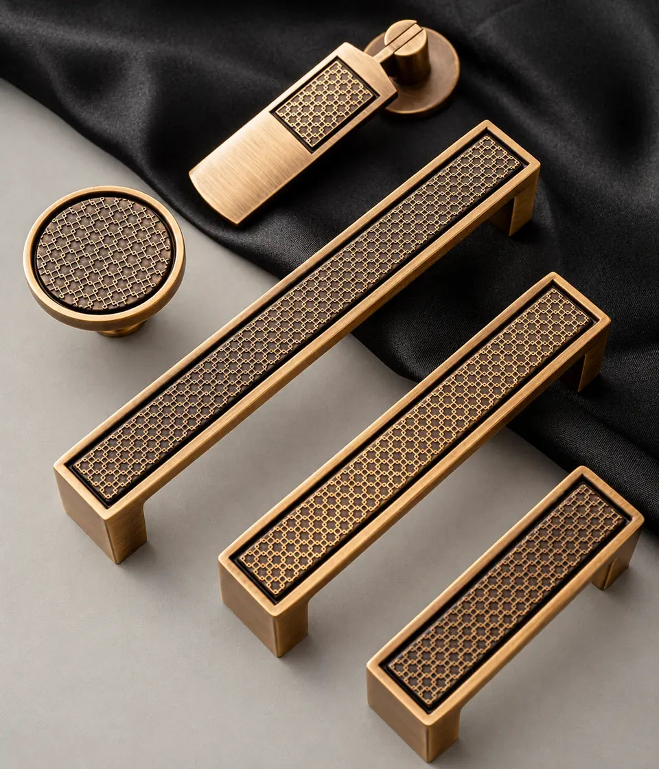 Antique brass lattice cabinet pulls, round knob and hanging pendant arranged on dark fabric