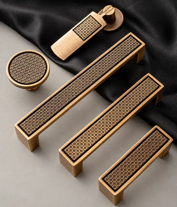 Antique brass lattice cabinet pulls, round knob and hanging pendant arranged on dark fabric