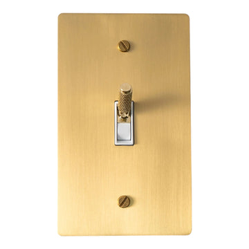 Satin-brass single-gang plate with a brass knurled toggle, white plastic insert and brass mounting screws