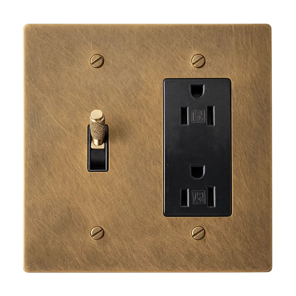 Two-gang unlacquered antique brass (hand-brushed) plate with one brass knurled toggle switch with a black plastic insert and one black regular 15A duplex outlet.