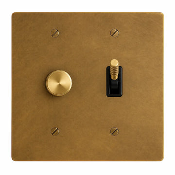 2-gang unlacquered antique brass (hand-brushed) plate. One 250W single-pole brass rotary dimmer on the left and one brass knurled toggle with a black plastic insert on the right.