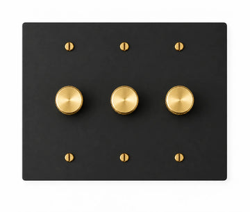 Black three-gang plate with three brass rotary dimmer knobs and six brass screws