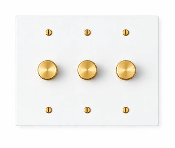 White three-gang plate with three brass rotary dimmer knobs and six brass screws