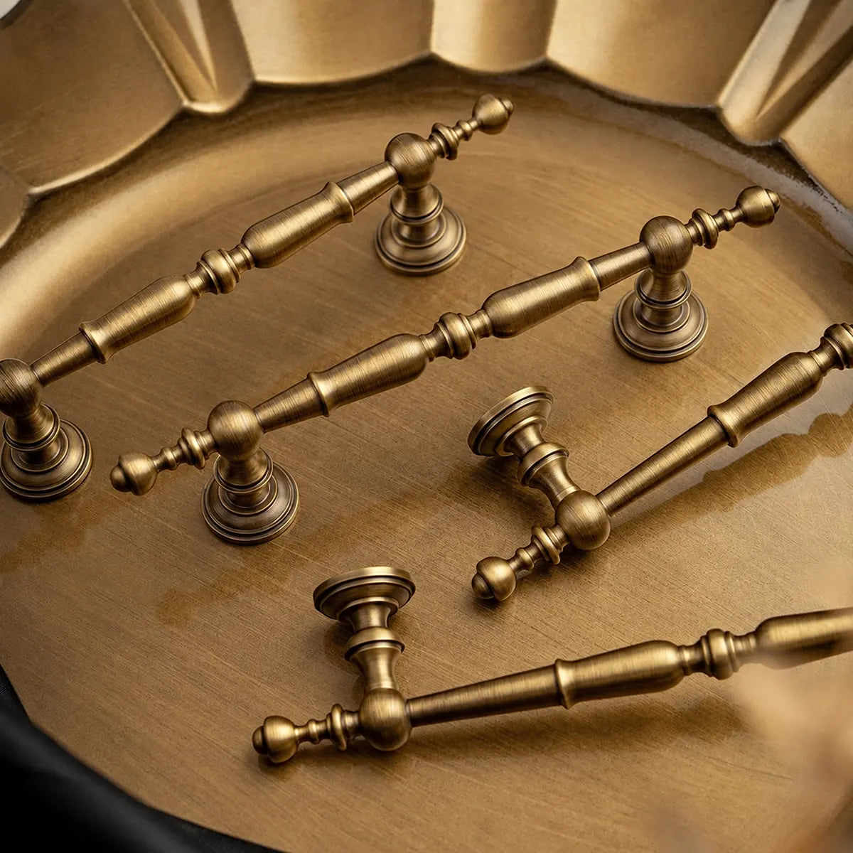 Antique brass ornate spindle pulls arranged on a tray
