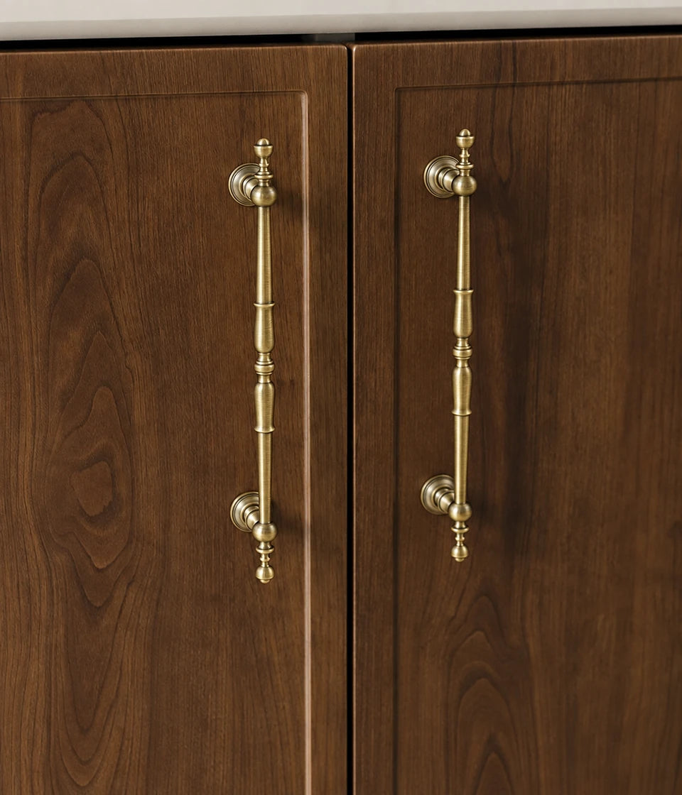 Ornate spindle antique brass cabinet pulls installed on dark wood doors