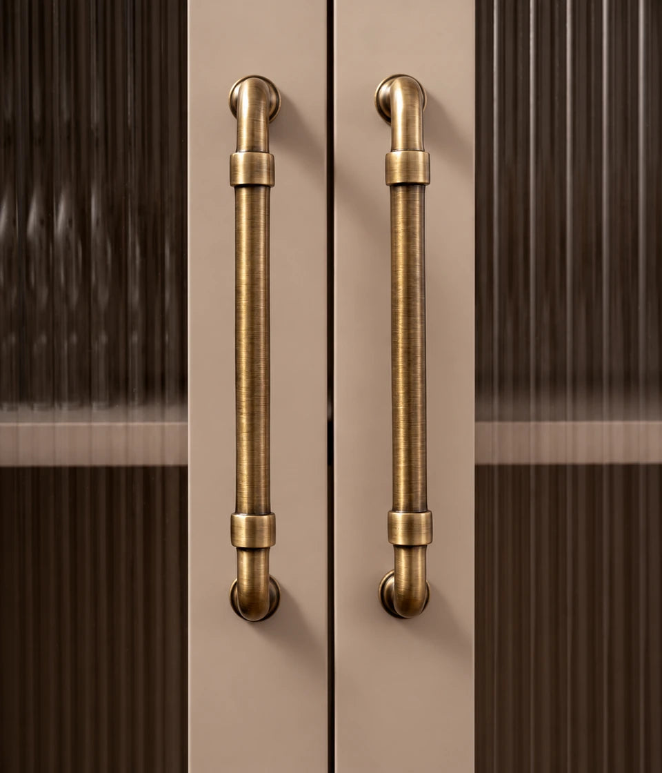 Antique brass pipe cabinet pulls installed vertically on fluted glass cabinet doors
