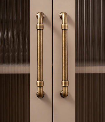 Antique brass pipe cabinet pulls installed vertically on fluted glass cabinet doors