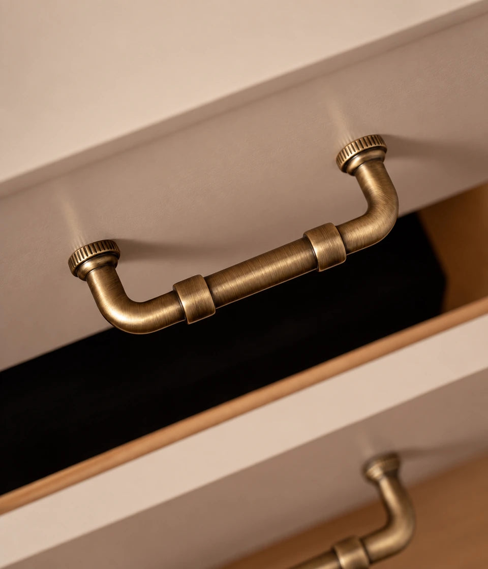 Antique brass pipe pull with ridged feet on a drawer