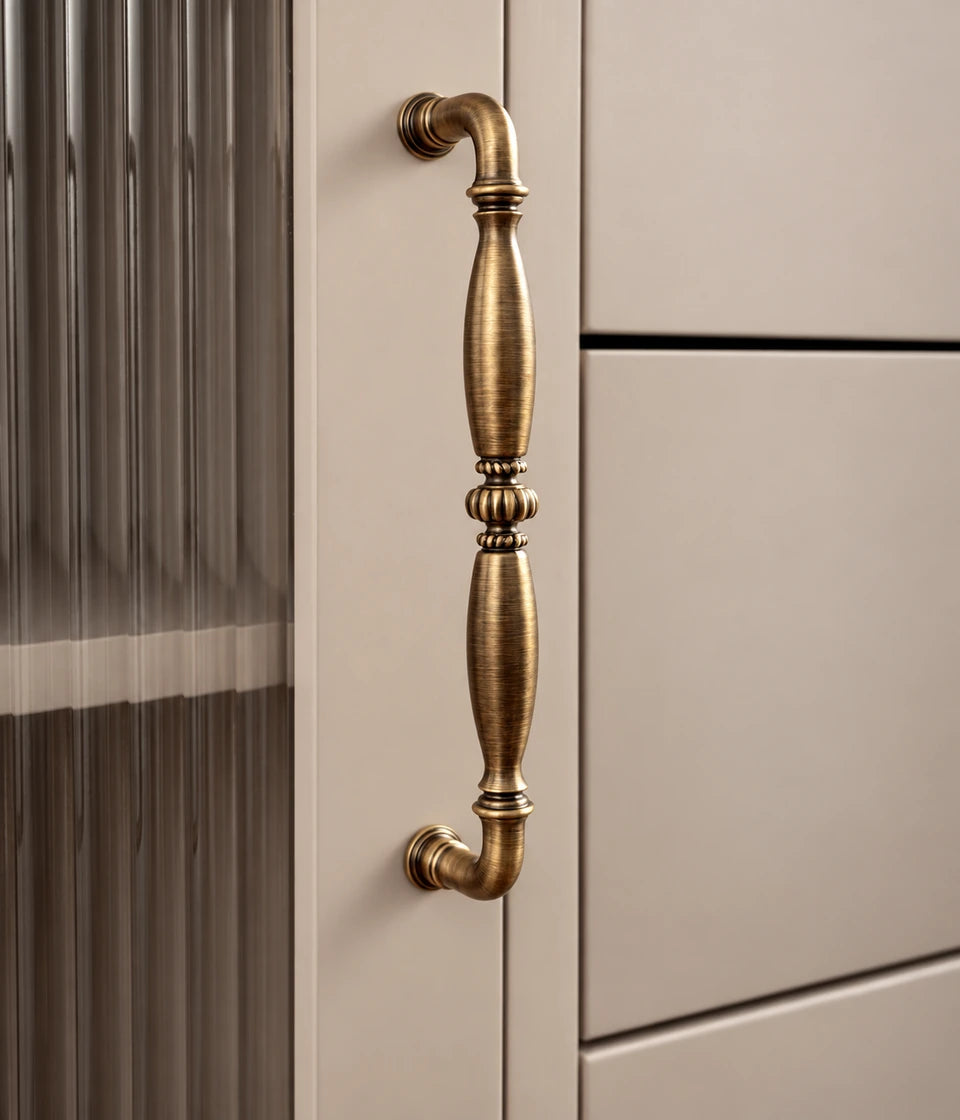 Antique brass cabinet pull with tapered grips and ribbed center installed vertically