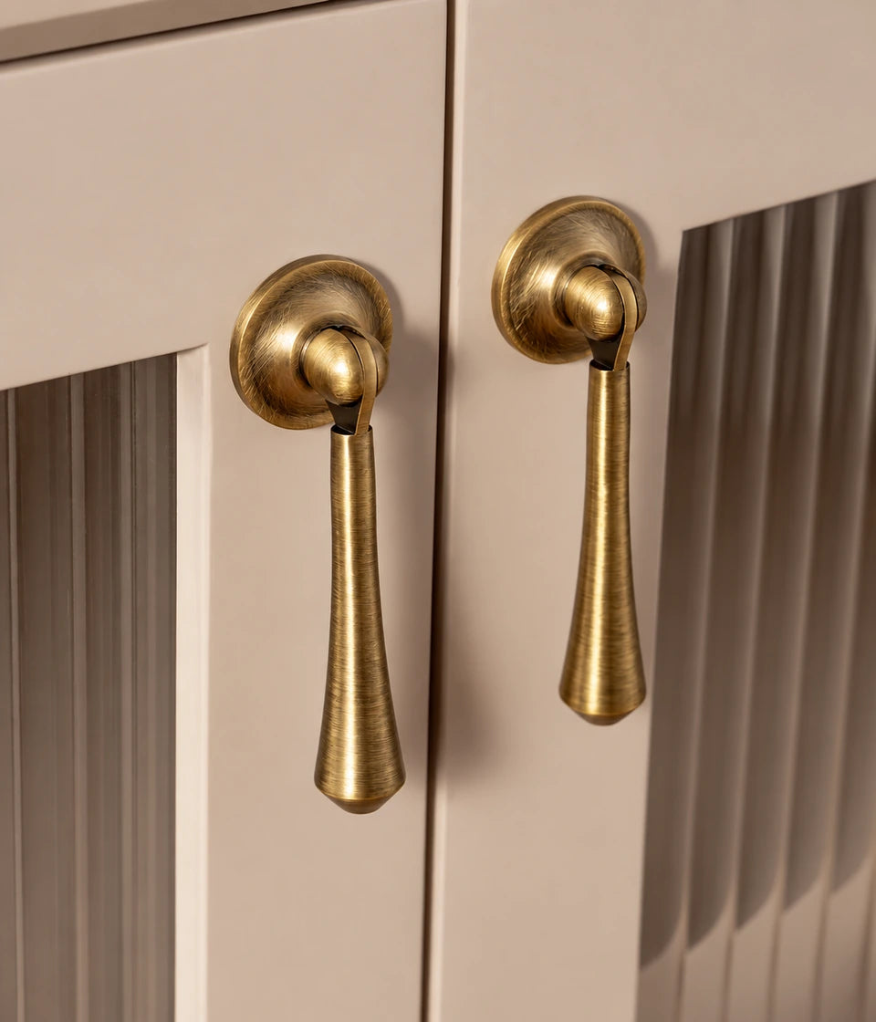 Antique brass pendant pulls with round backplates installed on cabinet doors