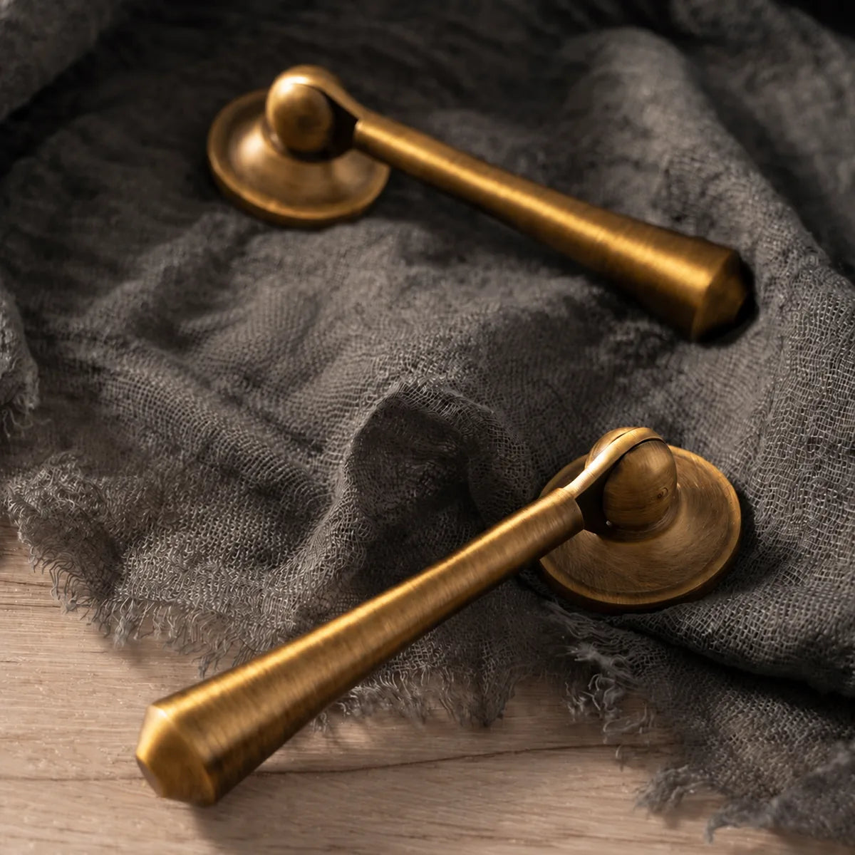 Antique brass pendant pulls and round mounting backplates on gray linen