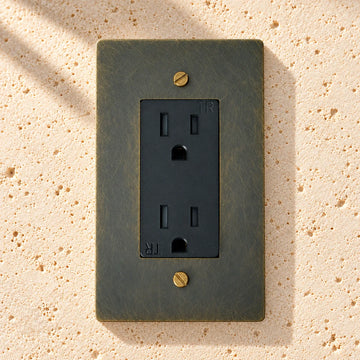 Solid Brass Duplex Outlet on sunlit pale limestone