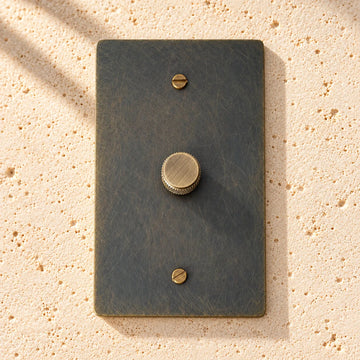 1-Gang Solid Brass Knurled Rotary Dimmer Light Switch on sunlit pale limestone