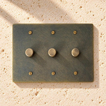 3-Gang Solid Brass Knurled Rotary Dimmer Light Switch on sunlit pale limestone