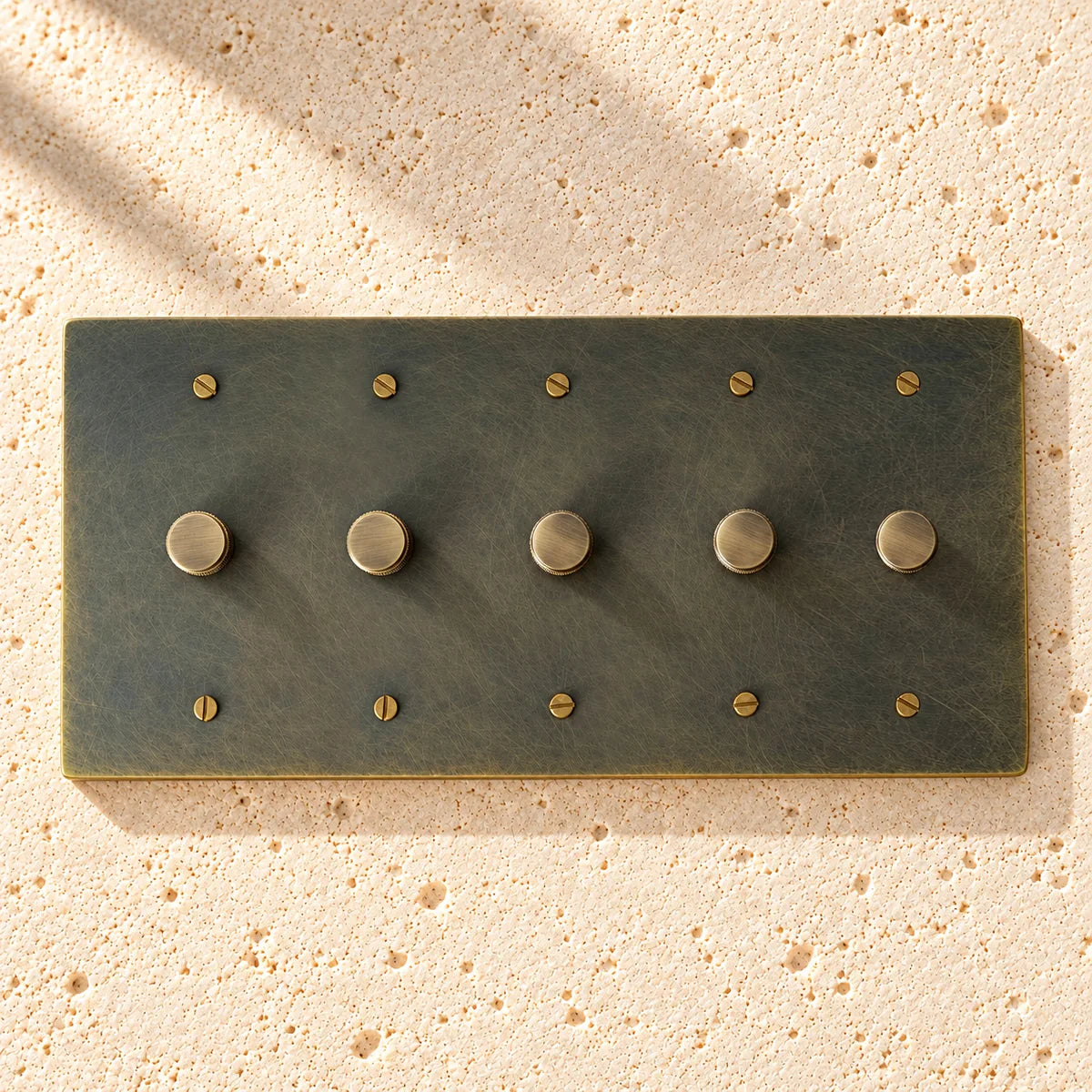5-Gang Solid Brass Knurled Rotary Dimmer Light Switch on sunlit pale limestone