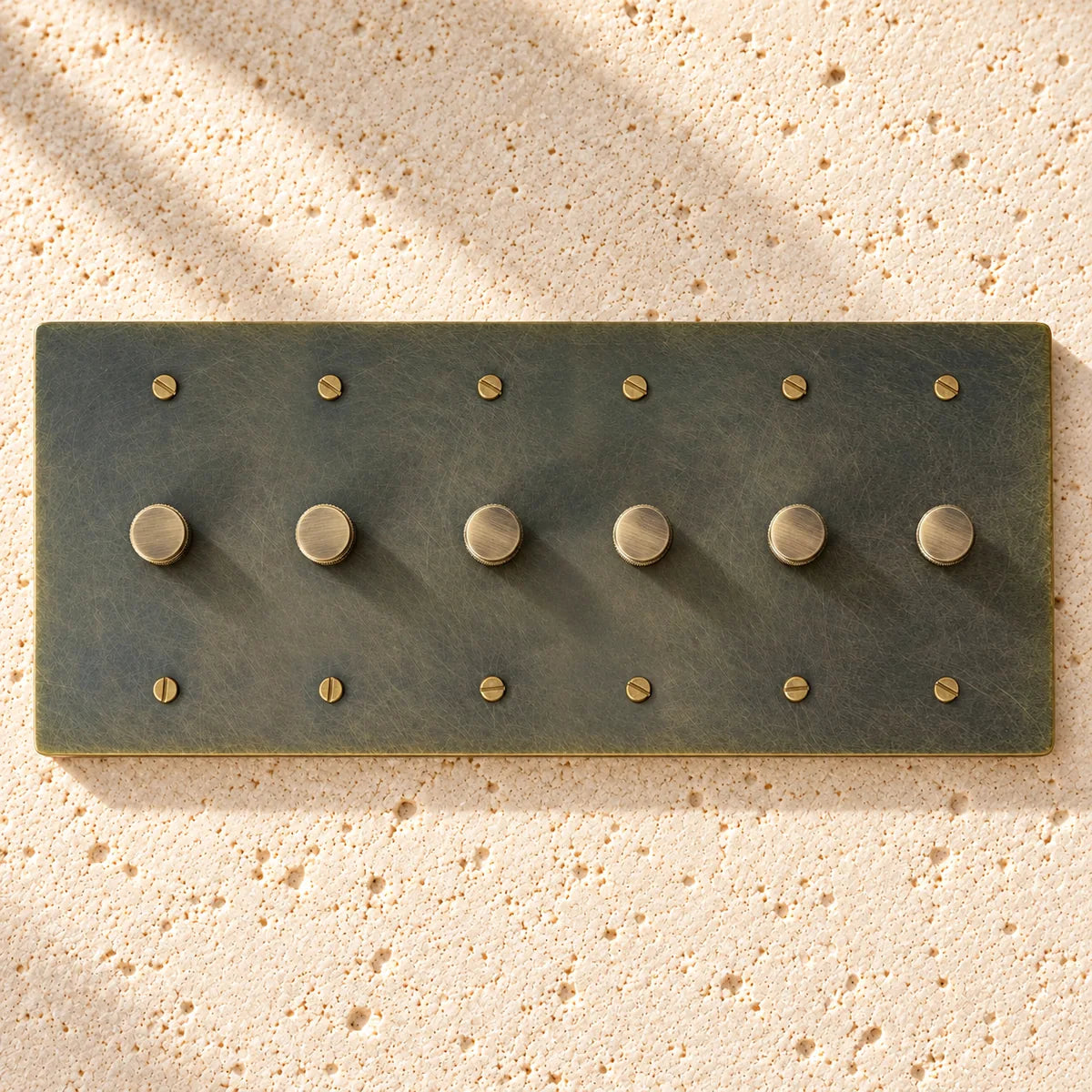 6-Gang Solid Brass Knurled Rotary Dimmer Light Switch on sunlit pale limestone