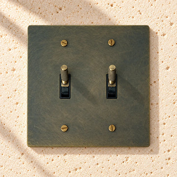 2-Gang Solid Brass Knurled Toggle Light Switch on sunlit pale limestone