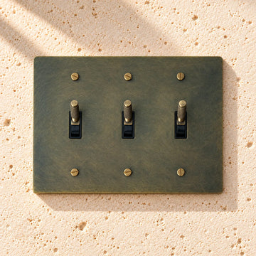3-Gang Solid Brass Knurled Toggle Light Switch on sunlit pale limestone
