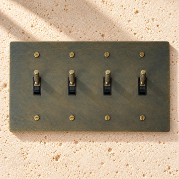 4-Gang Solid Brass Knurled Toggle Light Switch on sunlit pale limestone