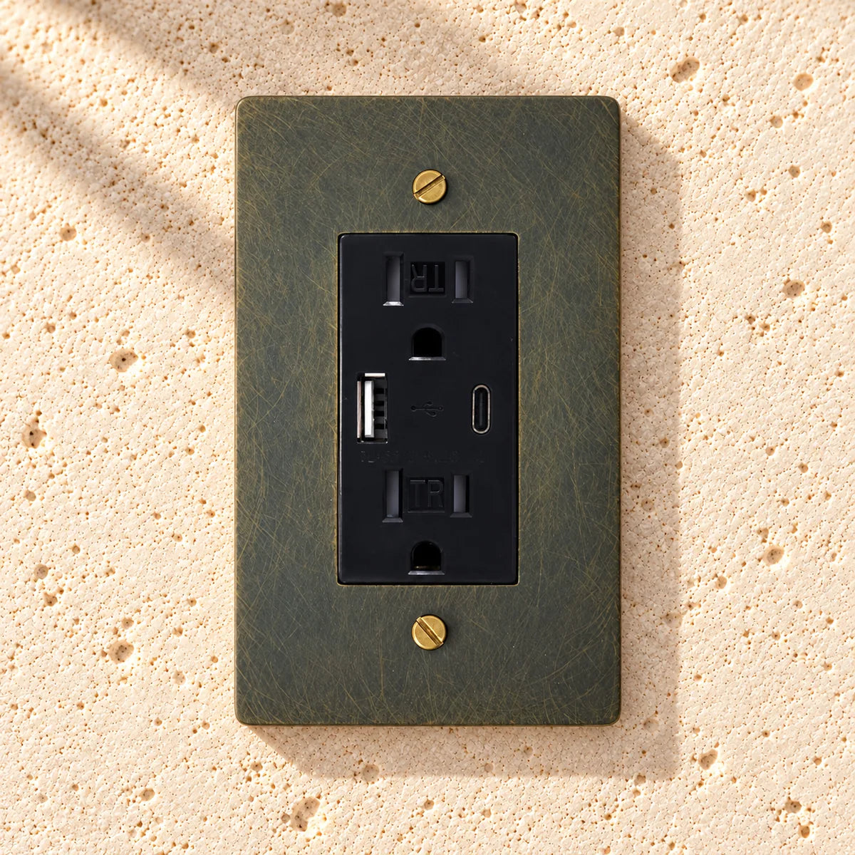 Solid Brass USB-A + USB-C Charging Outlet on sunlit pale limestone
