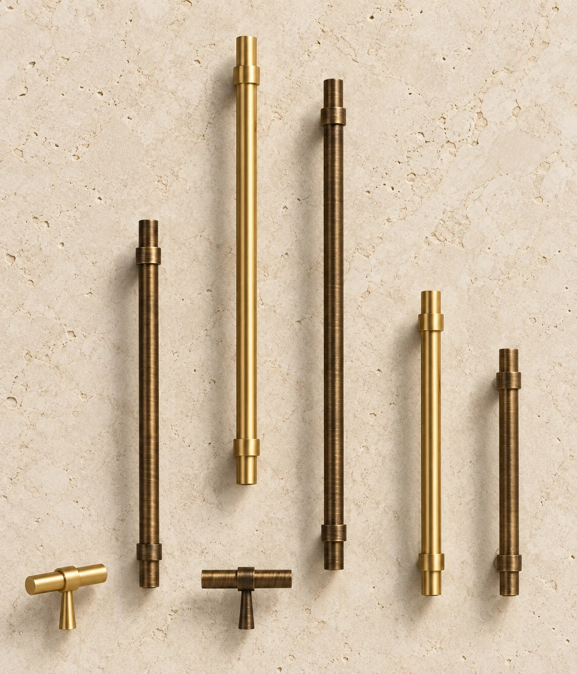 Stepped-Ring Brass Cabinet Pulls & T-Knobs arranged on warm limestone
