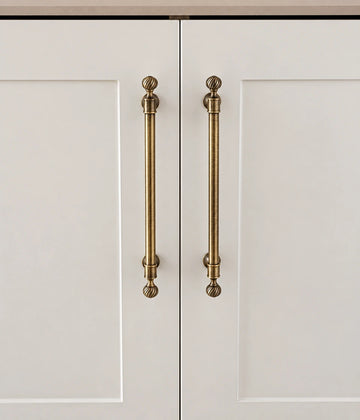 Antique brass swirl finial cabinet pulls installed on cream doors