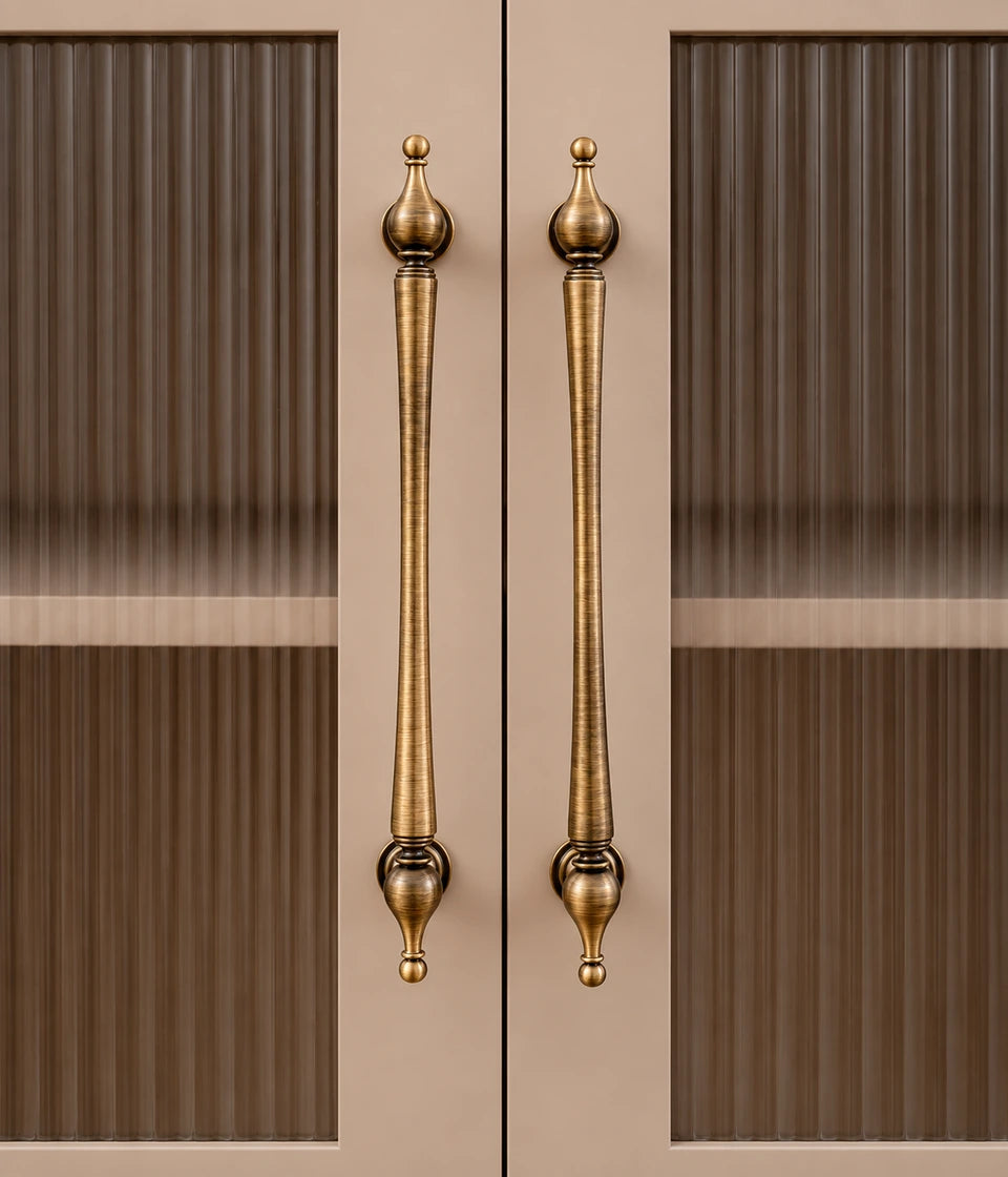 Long antique brass urn-finial cabinet pulls installed on glass-panel doors