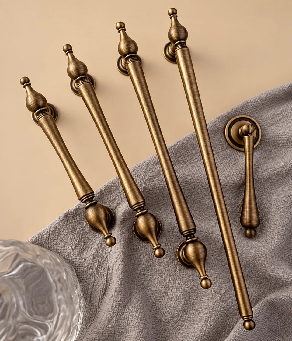 Antique brass urn-finial bar pulls and tapered pendant arranged on fabric