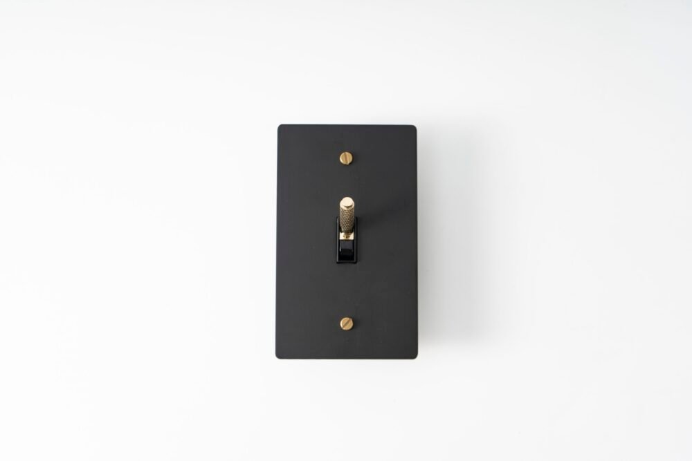 Black Brass Plate with Golden Knurled Toggle Switch - Sleek design combining black brass finish with a golden knurled switch for a sophisticated touch