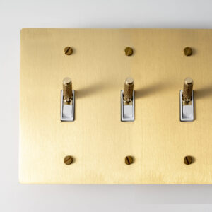 Satin Gold Knurled Three-Gang Toggle Switch - Textured triple switch panel with a stylish gold finish.