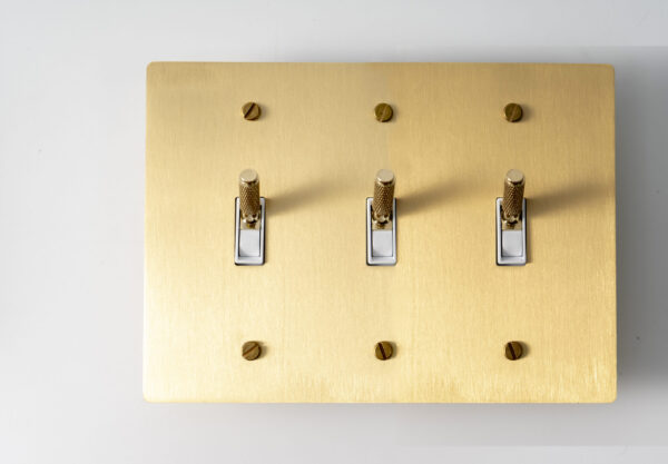 Satin Gold Knurled Three-Gang Toggle Switch - Textured triple switch panel with a stylish gold finish.