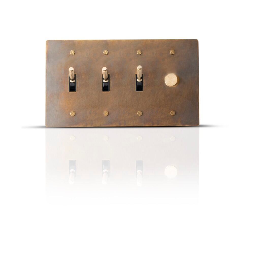 A sophisticated brass combo plate featuring three toggle switches and one dimmer control, elegantly designed for versatile lighting management in stylish interiors.